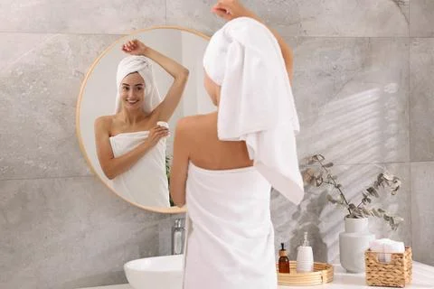 Smiling woman applying solid deodorant near mirror at home, back view Stockfoto's