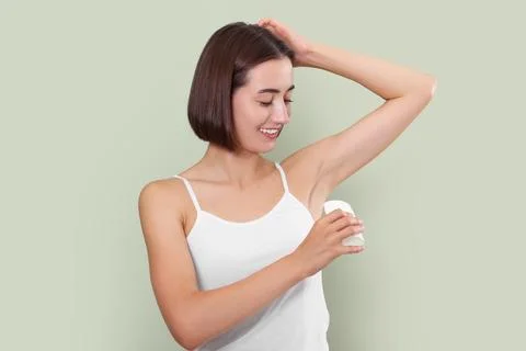 Smiling woman applying solid deodorant on green background Stockfoto's