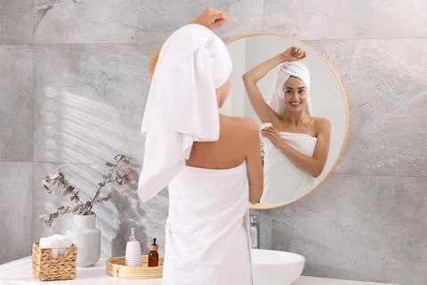 Smiling woman applying solid deodorant near mirror at home, back view Stockfoto's
