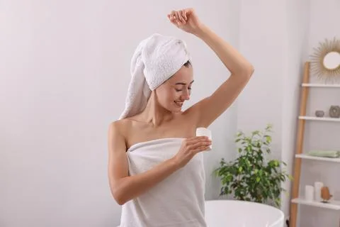 Smiling woman applying solid deodorant at home Stockfoto's