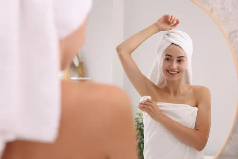 Smiling woman applying solid deodorant near mirror at home Stock Photos