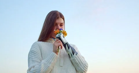 A smiling woman with a bionic hand sniffs a bouquet of wild flowers Stock Footage 159906233