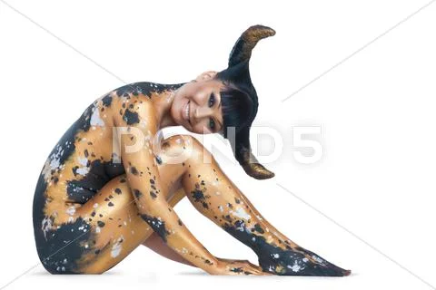 Smiling woman with bodypainting and hair horns sitting and looking at camera Stock Photos