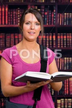 Smiling woman with a book in library Stock Photos