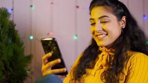 Smiling woman browsing mobile while sitting in a beautifully decorated room Video stock 145790050