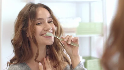 Smiling woman brushing teeth front mirror in bathroom. Dental and oral hygiene Stock Footage 108791585