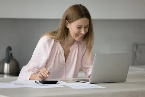 Smiling woman calculates incomes, expenses on calculator pay bills online Stock Photos