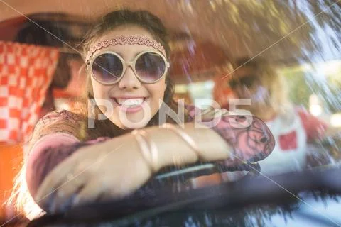 Smiling woman in camper van seen through windshield Stock Photos