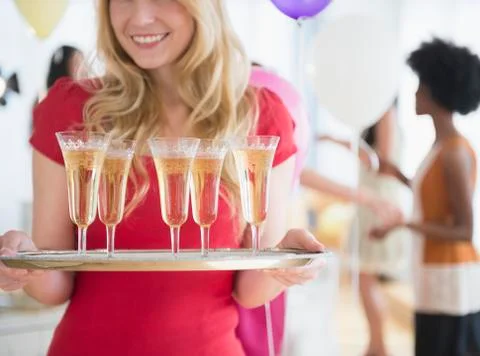 Smiling woman carrying tray of champagne Stock Photos