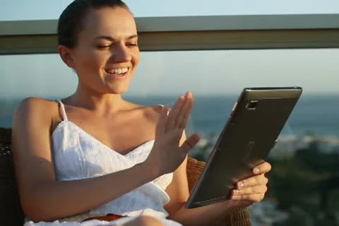 Smiling woman chatting on tablet while relaxing on terrace NTSC Stock Footage 10888674