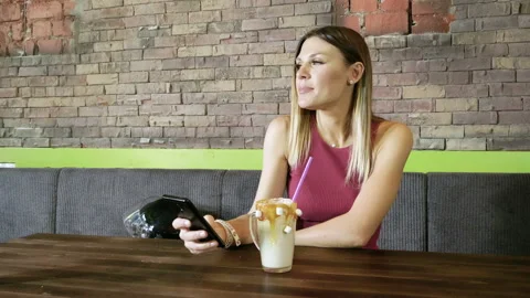 Smiling woman drinking coffee, using smartphone, texting on mobile phone. 4K 库存影片 97110628