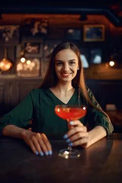 Smiling woman drinks coctail at the counter in bar Stock Photos