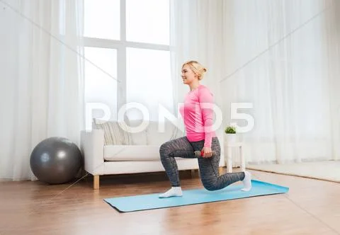 Smiling woman with dumbbells exercising at home Stock Photos