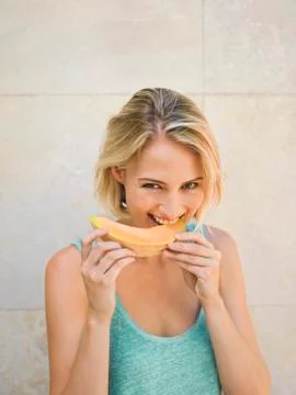 Smiling woman eating melon Stock Photos