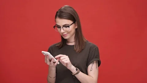 Smiling woman in glasses using smartphone isolated Stock Footage