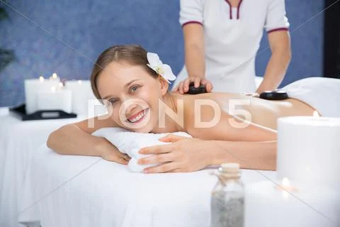 Smiling woman having stone massage in spa salon Stock Photos