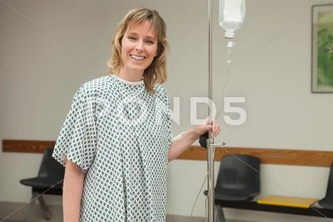 Smiling woman holding a drip stand while walking Stock Photos