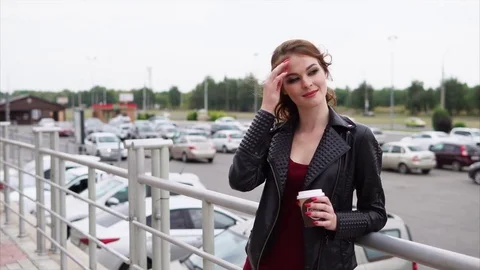 Smiling woman holding a glass of coffee in her hands and looking to the distance Stock Footage
