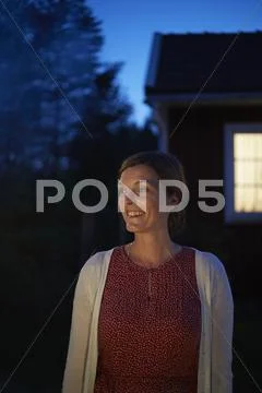 Smiling woman looking away in dark backyard Stock Photos