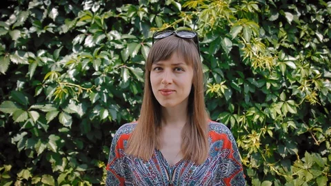 Smiling woman looking at camera in front of ivy wall background, portrai Stock Footage 127760243