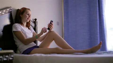 Smiling woman lying in bed using her mobile smartphone touchpad 스톡 동영상 48700596