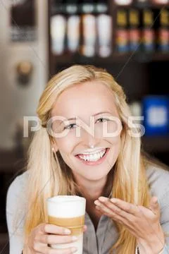 Smiling woman with milk foam at her face Stock Photos