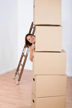 Smiling woman peering from behind stacked boxes Stock Photos