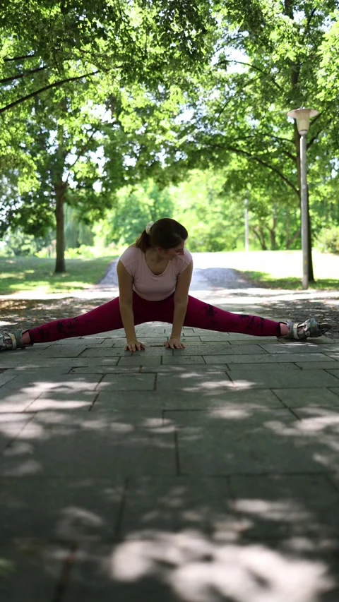 Smiling woman performs full split on roller skates in a green park Stock Footage 341476459