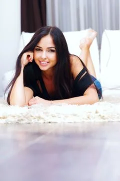 Smiling woman posing while lying on a carpet in the living room Stock Photos
