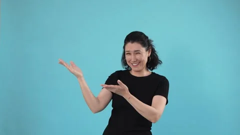 Smiling Woman Presenting Copy Space on Blue Studio Background Stock Footage 344778405