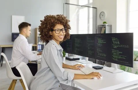 Smiling woman programmer working on code at desktop in bright tech office Fotos Stock