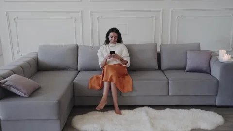 Smiling woman sitting on sofa while browsing Stock Footage 260074705