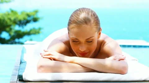 Smiling woman on spa bed next to swimming pool Stock Footage