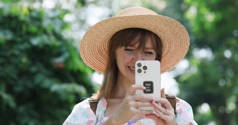 Smiling woman in straw hat using smartphone outdoors, sunny day, Stock-Footage 321825637