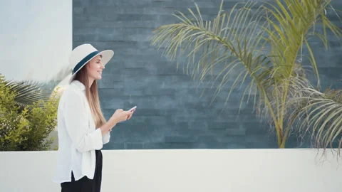 Smiling woman in summer hat using mobile outdoors Stock Footage 163599796