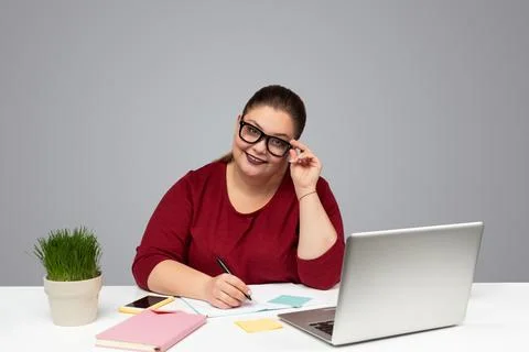 Smiling woman taking notes while working online on laptop Stock Photos