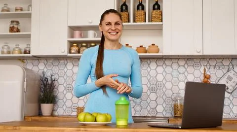 Smiling woman using computer in modern kitchen. Healthy lifestyle concept Stock Photos