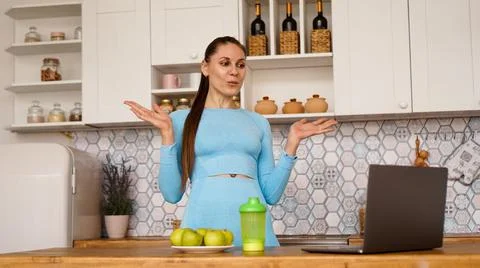 Smiling woman using computer in modern kitchen. Healthy lifestyle concept Stock Photos