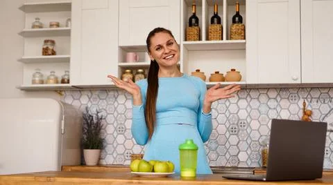 Smiling woman using computer in modern kitchen. Healthy lifestyle concept Stock Photos