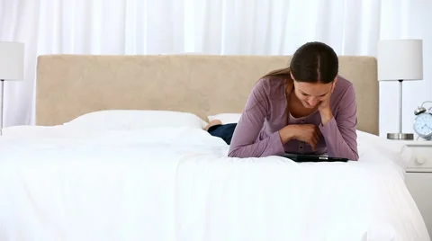 Smiling woman using a computer tablet lying on the bed Stockbeeldmateriaal 1017720