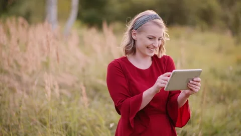 Smiling Woman Using Digital Tablet Outdoors in Summer Stock Footage 148303120
