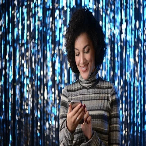 Smiling woman using her mobile phone over lights Stock Footage 69399893