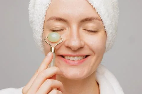 Smiling Woman Using Jade Roller for Facial Massage and Skin Care at Home Spa Stock Photos