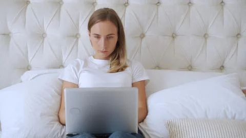 Smiling woman using laptop computer in the bed. Everyday use of technology Stock Photos