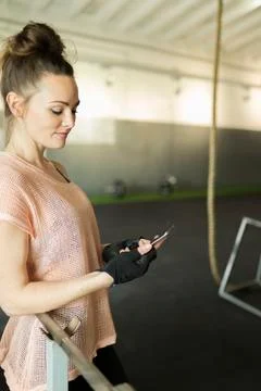 Smiling woman using smart phone while standing in gym Stock Photos
