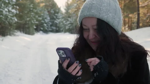 Smiling woman using smartphone in forest during winter Stock Footage 296677985