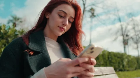 Smiling Woman Using Smartphone on Park Bench Stock Footage 303286742