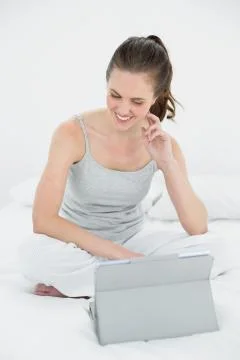 Smiling woman using tablet PC in bed Foto stock