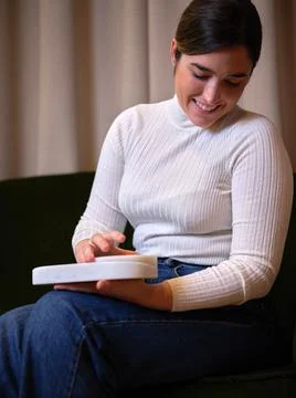 Smiling woman in a white pullover sitting using her new product Stock Photos