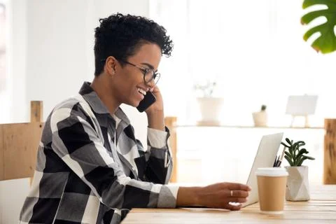 Smiling woman working using computer and phone in office Foto stock